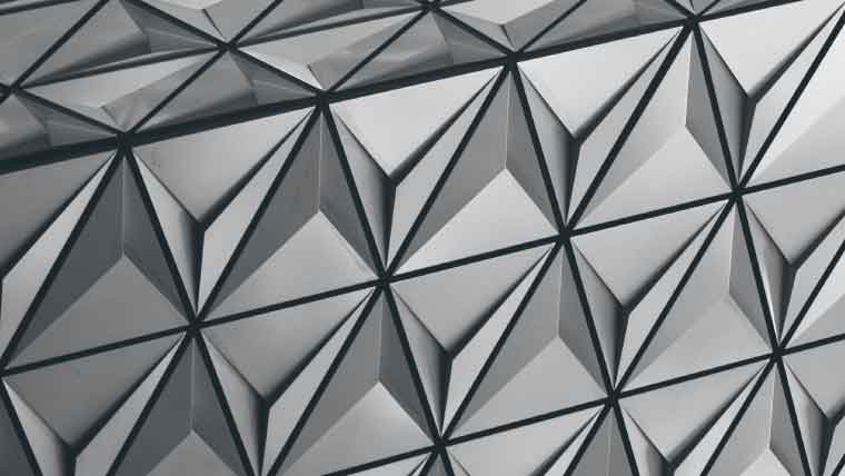 Geometric abstract art featuring a pattern of interconnected, three-dimensional triangular shapes in shades of gray, creating a complex and visually engaging design. The shapes exhibit a sense of depth and texture, resembling a modern, sculptural surface.