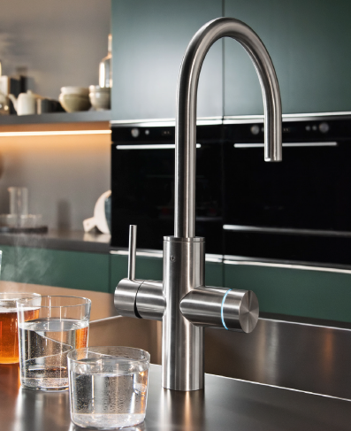 Un grifo monomando de cocina Franke de acero inoxidable sobre una encimera, con vasos de agua al lado