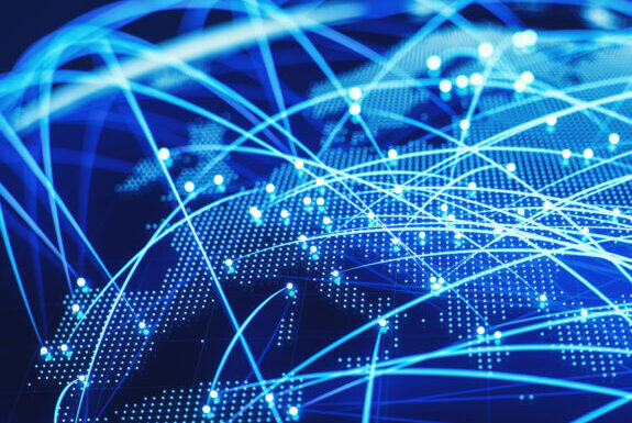 Représentation numérique d'un globe avec des lignes et des points bleus illustrant la connectivité mondiale. Les lignes s'entrelacent à travers les continents, suggérant des réseaux de données ou de communication couvrant le monde entier.